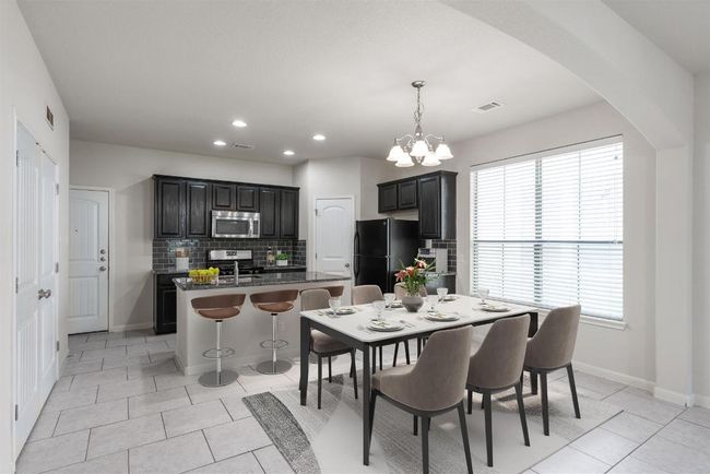 Kitchen features island with bar seating and dining area features a chandelier. | Image 4
