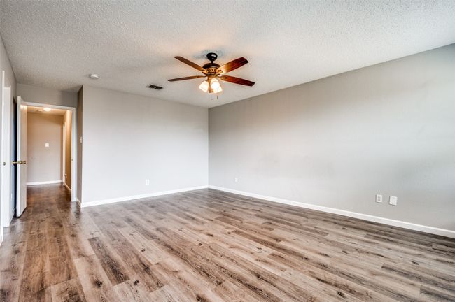Empty room featuring wood finished floors, ceiling fan, a textured ceiling, baseboards, and a smoke detector | Image 22