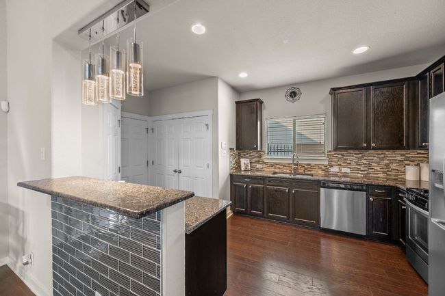Kitchen with stainless steel appliances, a sink, dark brown cabinets, dark wood-style floors, and recessed lighting | Image 11