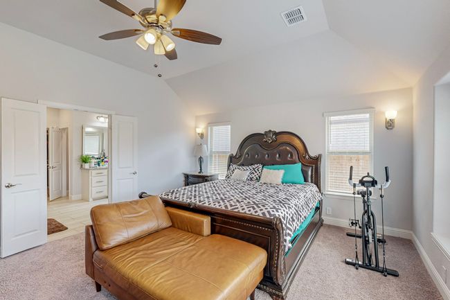 Carpeted bedroom featuring ceiling fan, baseboards, vaulted ceiling, and visible vents | Image 14