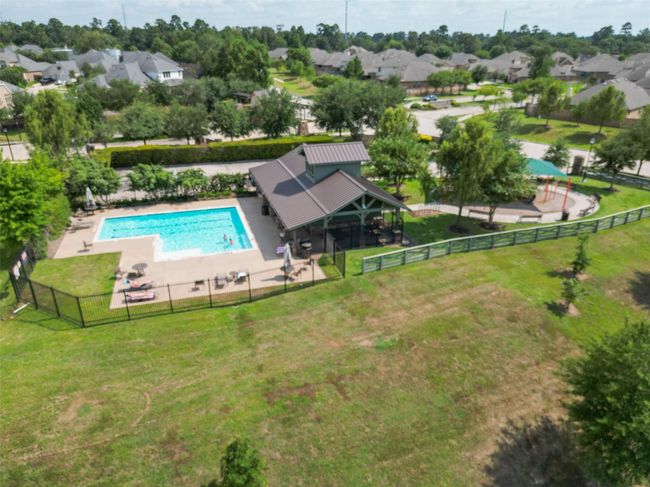 The community area featuring a swimming pool, a covered pavilion, and a playground, surrounded by lush greenery and nestled within a suburban neighborhood. Perfect for family-friendly living. | Image 35