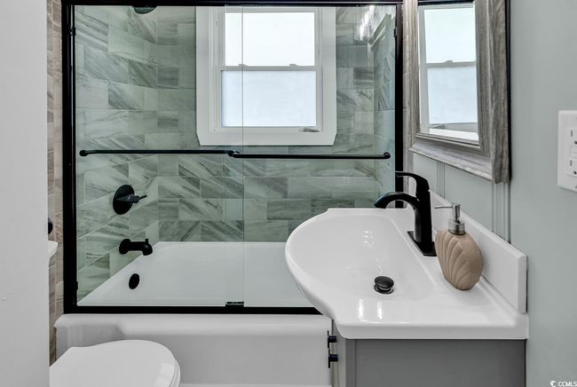 Full bathroom featuring vanity, a healthy amount of sunlight, shower / bath combination with glass door, and toilet | Image 26