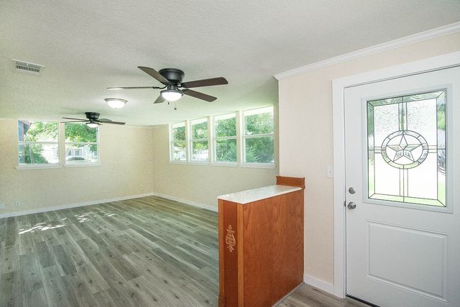 Entrance foyer with wood finished floors, healthy amount of natural light, ceiling fan, a textured ceiling, and ornamental molding | Image 6