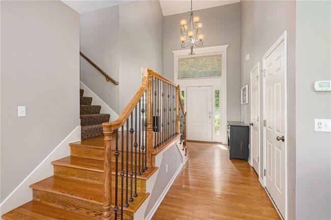 Foyer entrance featuring a towering ceiling, stairway, a chandelier, and light wood-type flooring | Image 4