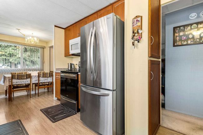 Kitchen featuring a notable chandelier, light countertops, light wood finished floors, brown cabinetry, and stainless steel appliances | Image 16