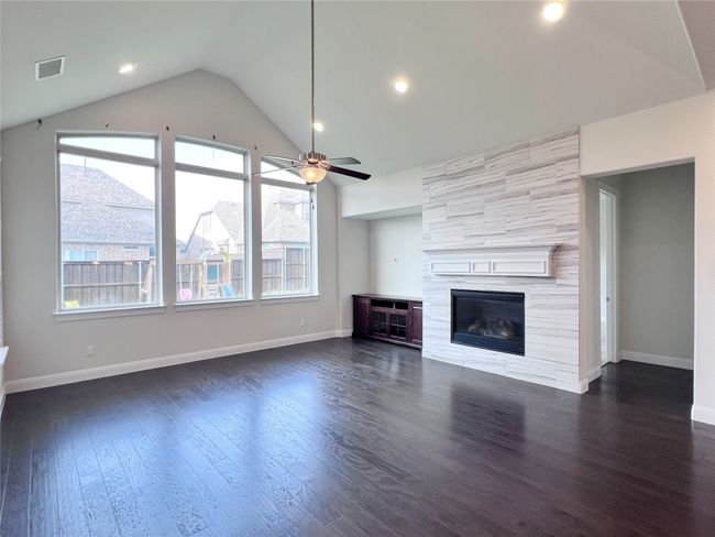 Unfurnished living room featuring ceiling fan, dark wood-type flooring, a large fireplace, lofted ceiling, and recessed lighting | Image 18
