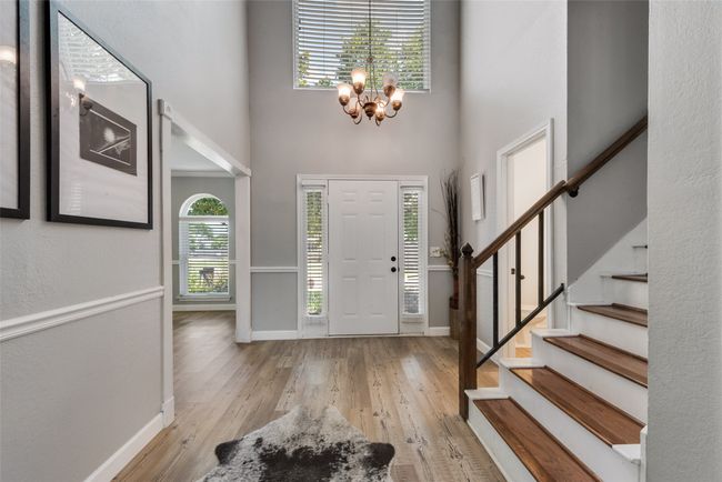 Foyer entrance featuring a high ceiling, stairway, a chandelier, and hardwood / wood-style flooring | Image 5