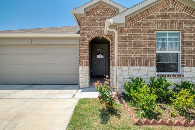 View of front of home with driveway, a garage, brick siding, stone siding, and roof with composite shingles | Image 4