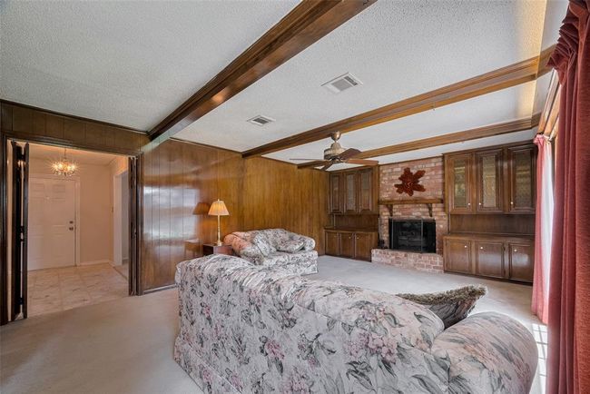 Cozy family room featuring elegant wood paneling and a charming brick fireplace. | Image 15