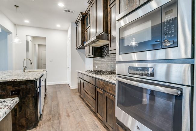 Kitchen featuring appliances with stainless steel finishes, dark brown cabinetry, light wood-style floors, and recessed lighting | Image 7