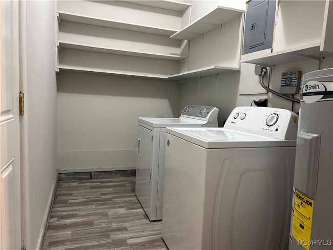 Laundry room featuring laundry area, separate washer and dryer, wood finished floors, baseboards, and electric panel | Image 7