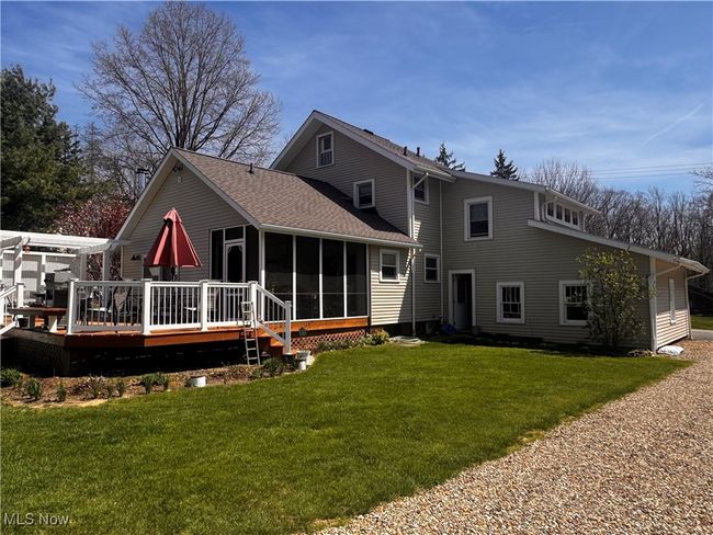 Rear view of property featuring a wooden deck, a shingled roof, a yard, and a sunroom | Image 4