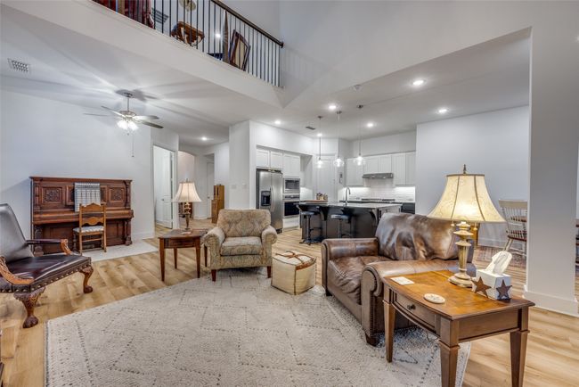 Living room with a towering ceiling, visible vents, ceiling fan, and light wood-style flooring | Image 7