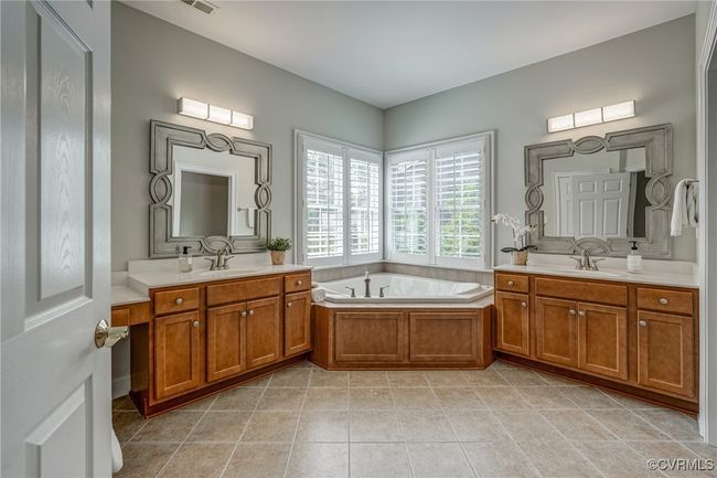 Luxurious en-suite bath with tile flooring, a soaking tub, double vanity, and a walk-in tile shower—designed for everyday indulgence. | Image 35
