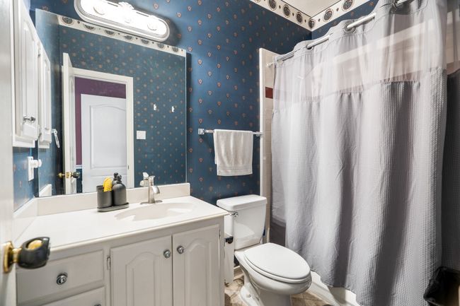 Bathroom featuring curtained shower, wallpapered walls, toilet, and vanity | Image 27