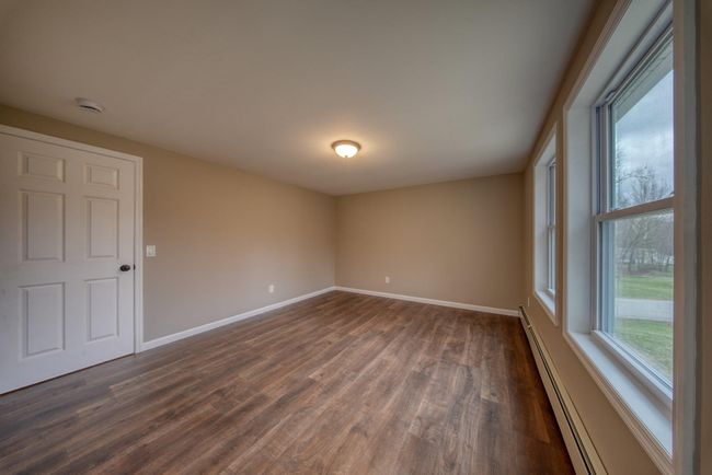 Empty room with a baseboard heating unit, baseboards, and dark wood-style floors | Image 16