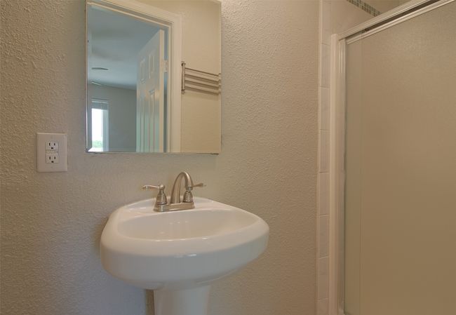 Bathroom with a textured wall, a sink, and a stall shower | Image 17