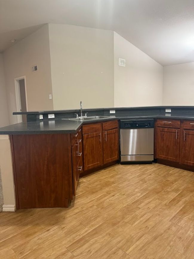 Kitchen with stainless steel dishwasher, light wood-type flooring, and dark countertops | Image 8