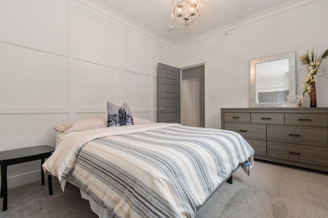 Bedroom featuring a decorative wall, a notable chandelier, light colored carpet, and ornamental molding | Image 21