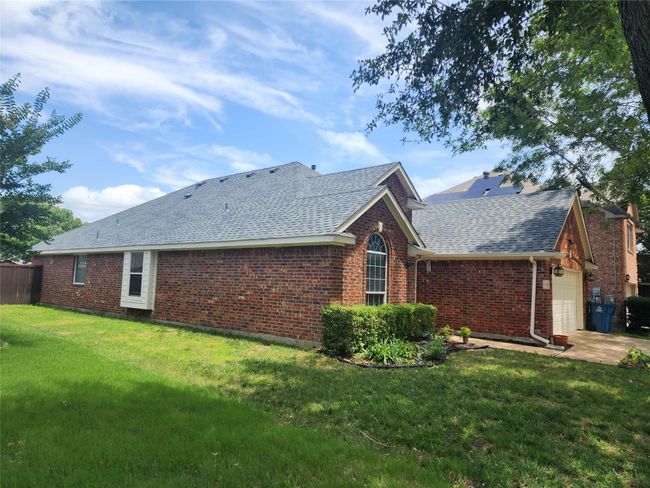 Rear view of property with new roof with shingles, brick siding, a garage, and a lawn | Image 23