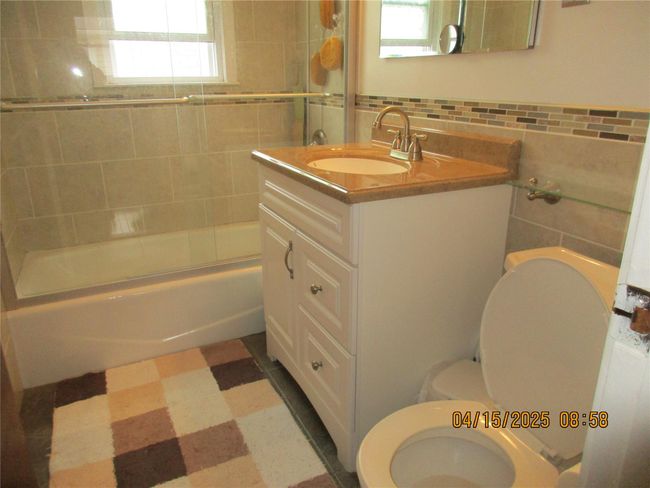 Full bath featuring vanity, enclosed tub / shower combo, tile patterned floors, toilet, and tile walls | Image 11