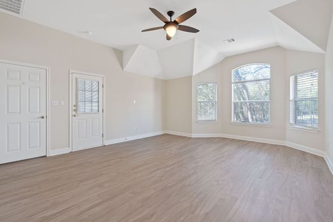 Unfurnished living room featuring light wood-type flooring, lofted ceiling, ceiling fan, and visible vents | Image 20