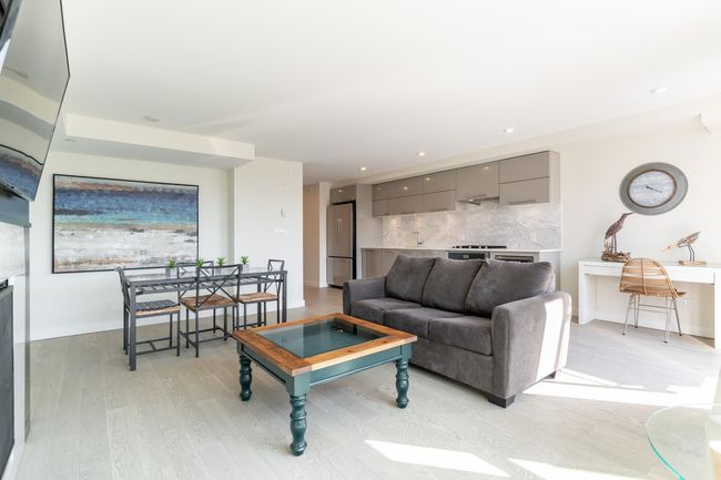 Living room with recessed lighting, a glass covered fireplace, light wood finished floors, and baseboards | Image 13