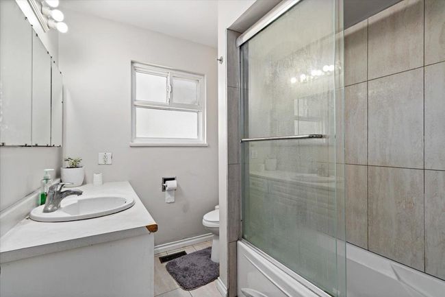 Full bathroom with visible vents, tile patterned floors, toilet, enclosed tub / shower combo, and vanity | Image 21