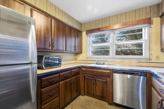 Kitchen with appliances with stainless steel finishes, a sink, wallpapered walls, and light countertops | Image 11