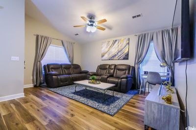 Living room with wood-type flooring, vaulted ceiling, ceiling fan, and plenty of natural light | Image 2