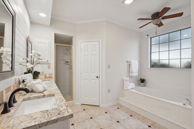 Primary Bathroom with a bath, double vanity, a stall shower, a ceiling fan, and tile patterned flooring | Image 21