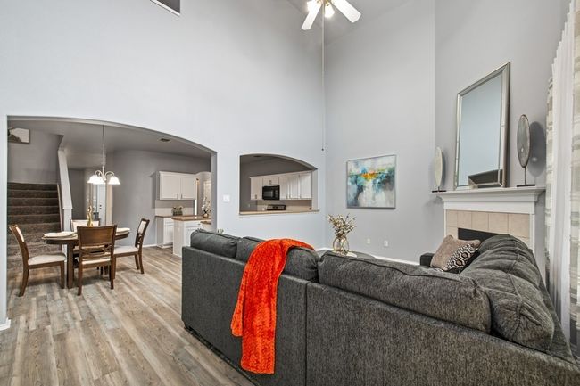 Living room featuring a high ceiling, a ceiling fan, stairway, light wood-style flooring, and a tile fireplace | Image 19