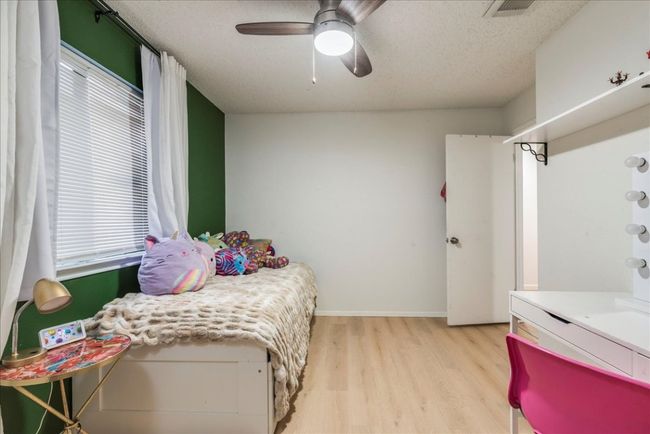 Bedroom featuring light wood finished floors, a textured ceiling, baseboards, visible vents, and ceiling fan | Image 15