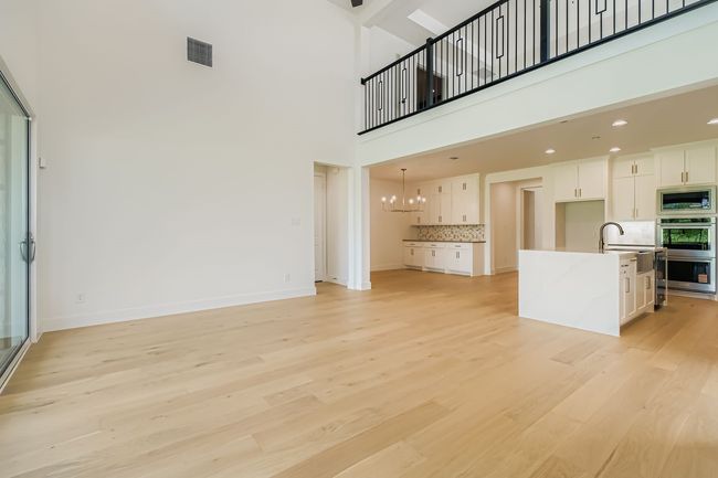Unfurnished living room featuring light wood finished floors, a chandelier, and a high ceiling | Image 6