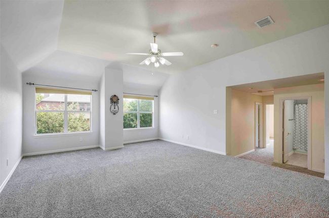 Unfurnished room with lofted ceiling, visible vents, baseboards, carpet, and a ceiling fan | Image 15