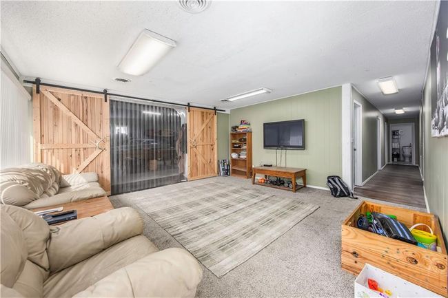 Living room featuring a barn door, visible vents, carpet floors, and a textured ceiling | Image 6