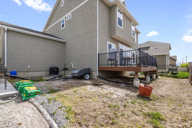 Rear view of property featuring central air condition unit, a deck, stucco siding, and fence | Image 28