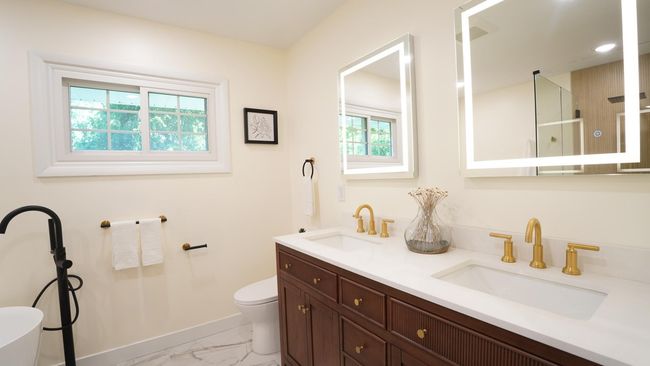 The owners' bath wood double vanity comes equipped with quartz countertops, two sinks, gold hardware and LED touch vanity mirrors. | Image 13