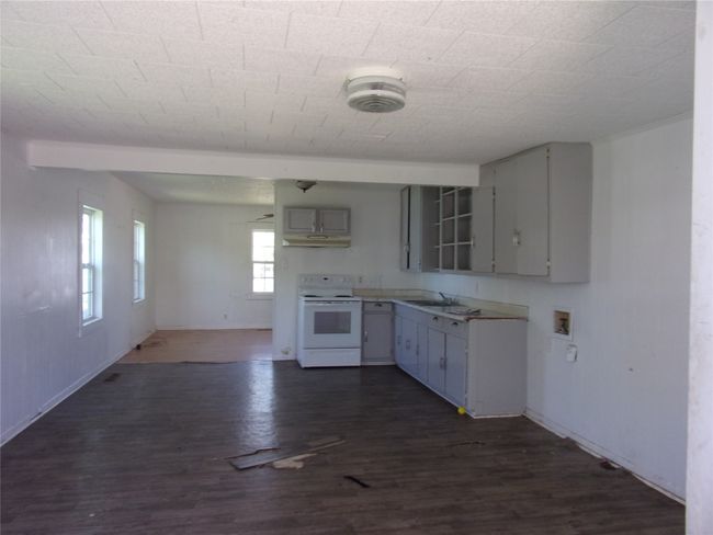 Kitchen with a sink, baseboards, white range with electric stovetop, and dark wood-style floors | Image 17