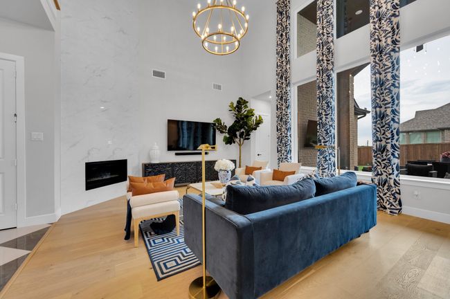 Living area featuring wood finished floors, a high ceiling, a chandelier, and a high end fireplace | Image 13