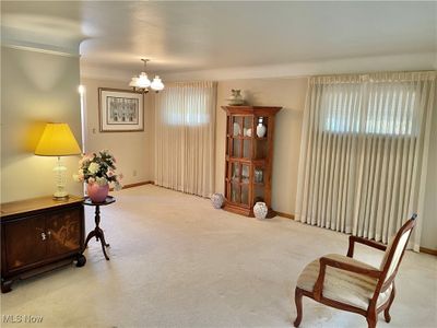 Living area with light carpet, an inviting chandelier, and ornamental molding | Image 3