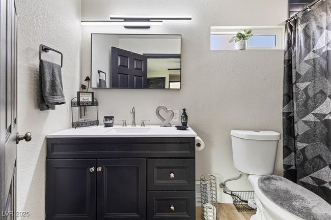 Bathroom with vanity, a shower with curtain, wood finished floors, toilet, and a textured wall | Image 18