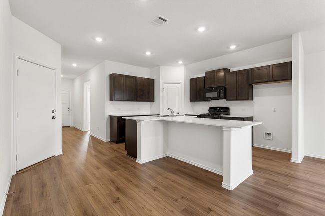 Kitchen with black microwave, range, wood finished floors, light countertops, and recessed lighting | Image 6