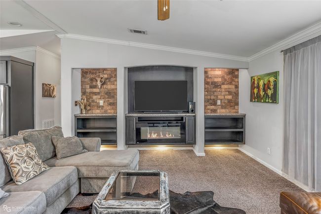 Carpeted living room with crown molding, visible vents, ceiling fan, and baseboards | Image 9