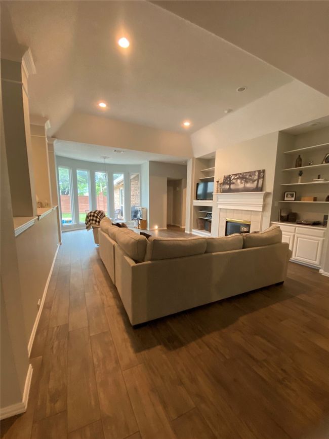 Living area featuring a tiled fireplace, built in features, baseboards, wood tiled floors, and recessed lighting | Image 6
