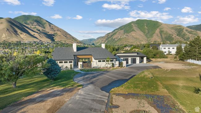 View of front of property featuring a chimney, asphalt driveway, a garage, a mountain view, and a front yard | Image 92