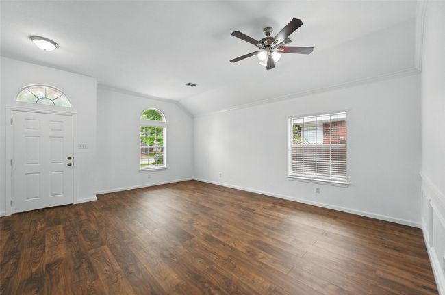 Entrance foyer with vaulted ceiling, dark wood-style flooring, a ceiling fan, and baseboards | Image 4