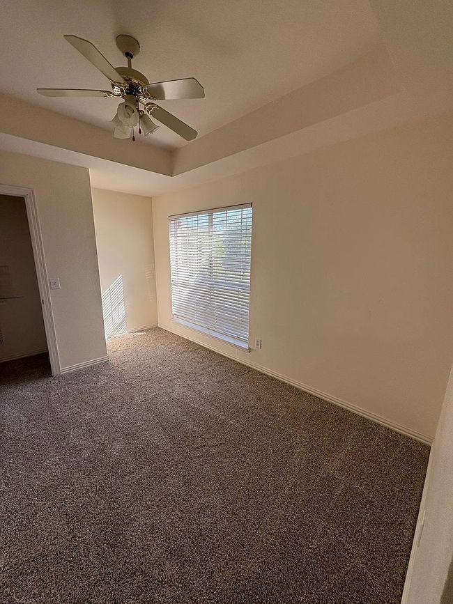 Empty room with a ceiling fan and carpet | Image 4