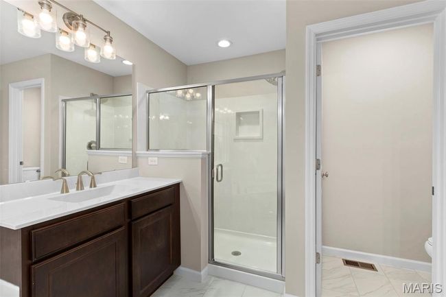 Bathroom featuring toilet, marble finish floors, a shower stall, vanity, and baseboards | Image 21