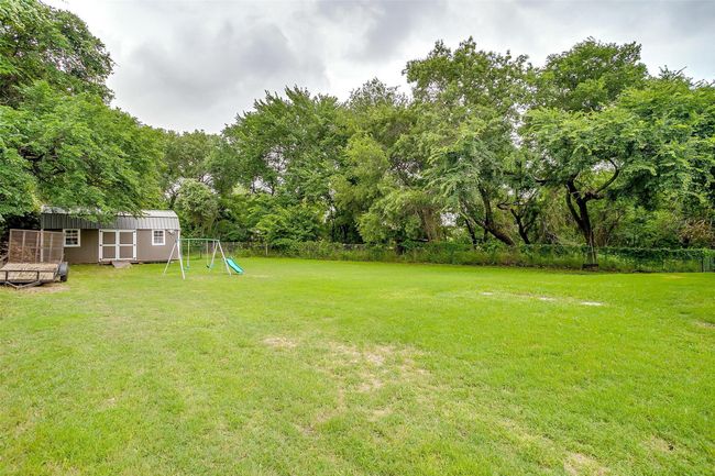 View of yard with a storage shed, a playground, and view of wooded area | Image 32